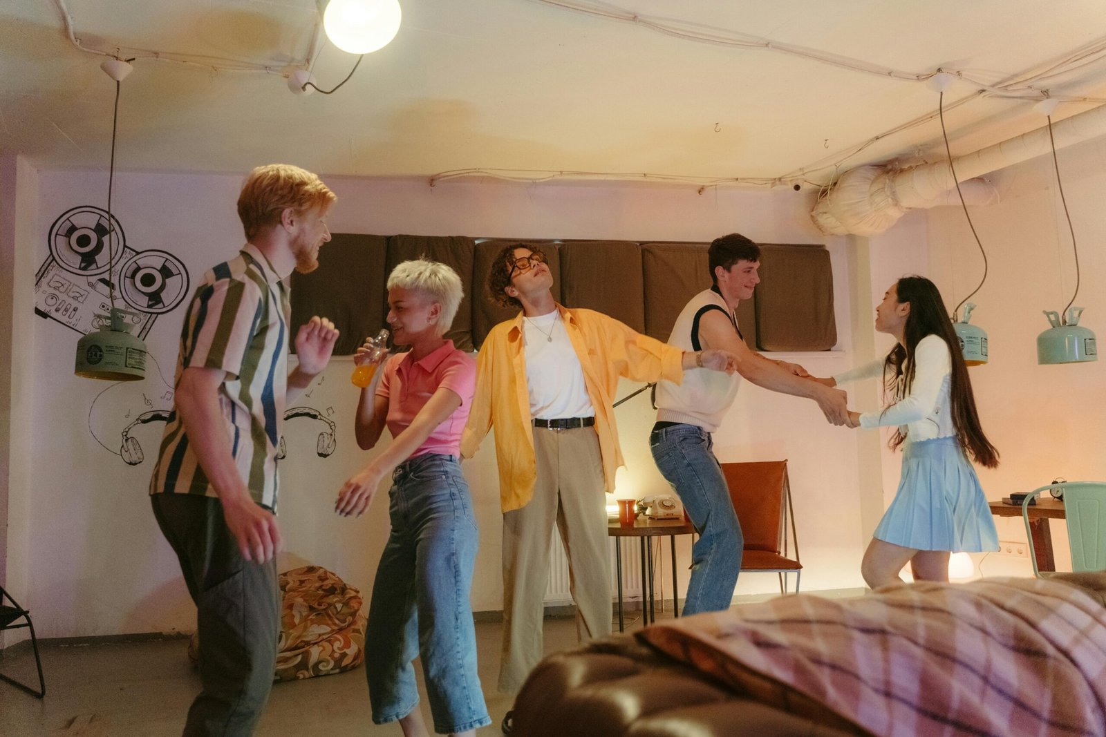 A group of young adults dancing and having fun at a retro-themed party indoors.